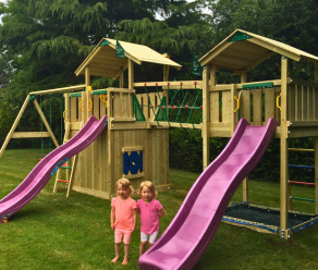 Holzspielturm mit zwei Rutschen, Kletternetz, Netzbrücke und Schaukeln in einem Garten